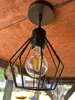 A black industrial-style pendant light with a clear Edison bulb hangs from a wooden ceiling. Produktbild-Vorschau