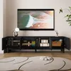 A modern living room scene featuring a black TV stand with open doors, displaying books and decorative items, with a television mounted on the wall above it. Náhľad obrázku produktu