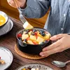 A person is eating a fruit salad from a black bowl. Náhled obrázku produktu