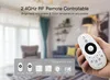 A hand holding a remote control in front of a blurred living room. Produktbild-Vorschau