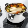 A stainless steel pressure cooker filled with chicken, corn, carrots, and other ingredients is placed on an induction cooktop. Produktbild-Vorschau