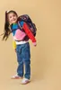 A young girl is wearing a backpack and smiling. Náhľad obrázku produktu