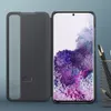 A dark gray flip case for a Samsung Galaxy S20 phone is shown open, revealing the phone's screen with a floral wallpaper. A pencil holder with pencils is visible on the right side. Náhľad obrázku produktu