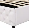 Close-up view of the corner of a white upholstered bed frame, showing the tufted headboard and wooden slats of the bed base. Produktbild-Vorschau