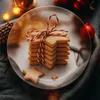 A stack of star-shaped cookies tied with red and white twine on a plate, surrounded by festive decorations. Produktbild-Vorschau
