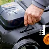 A person's hand is adjusting a lever on a lawn care machine. Produktbild-Vorschau
