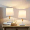 Two bedside lamps on a wooden nightstand with books and a glass of water. Náhľad obrázku produktu