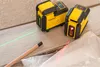 Two yellow Stanley laser levels are shown on a wooden surface, with green and red laser lines projected. Produktbild-Vorschau