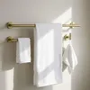 A set of gold-toned bathroom hooks with white towels hanging on them. Produktbild-Vorschau