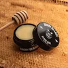 A jar of beard wax is placed on a honeycomb background, with a wooden honey dipper nearby. Produktbild-Vorschau