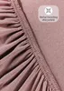 A close-up view of a pink fitted sheet, showing the elasticized edge. Produktbild-Vorschau