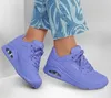 A pair of purple Skechers sneakers on a person's feet, with blue jeans visible. Náhled obrázku produktu