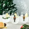 Three Christmas-themed glasses filled with a clear beverage and lemon slices, set against a blurred Christmas tree background. Produktbild-Vorschau