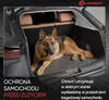 A German Shepherd dog is lying in the trunk of a car on a car mat. Produktbild-Vorschau