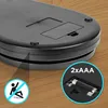 The underside of a black digital scale is shown on a wooden surface. There are two inset circles, one with a 'no falling' symbol and the other showing AAA batteries and the text '2xAAA'. Produktbild-Vorschau
