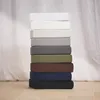 A stack of fitted sheets in various colors, arranged vertically against a white, textured background. Produktbild-Vorschau