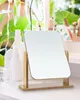A vanity mirror with a wooden stand is placed on a white surface, with cosmetic bottles and makeup brushes in the background. Produktbild-Vorschau