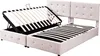 A beige upholstered bed frame with its mattress support system lifted to reveal storage space underneath. Produktbild-Vorschau