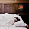 A person sleeping in a bed with a small electric heater mounted on the wall above the headboard. Anteprima dell’immagine prodotto