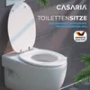 A white toilet seat with the lid up, set against a gray tiled wall. The brand name 'CASARIA' and product description are overlaid on the image. Anteprima dell’immagine prodotto