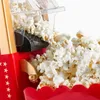 A close-up of a popcorn machine dispensing popcorn into a red container. Náhled obrázku produktu