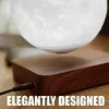 A close-up shot of a levitating moon lamp with a wooden base, plugged in with a power cord. Produktbild-Vorschau