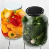 Two jars of preserved food, one with peppers and the other with pickles, are displayed on a white wooden surface. Voir les images du produit