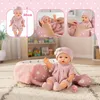 Collage of a baby doll and its accessories, including a bassinet, pillow, blanket, and pacifier, set against a soft pink and white background with heart motifs. Produktbild-Vorschau