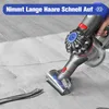 A hand is holding a vacuum cleaner attachment and vacuuming long dark hair from a light-colored rug on a wooden floor. Produktbild-Vorschau
