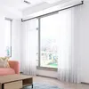 A living room scene with a pink sofa, a wooden coffee table, and sheer white curtains covering a large window. Produktbild-Vorschau