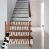 A dog is looking at a wooden pet gate placed at the bottom of a staircase. Another dog is peeking from a doorway in the background. Produktbild-Vorschau