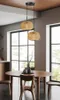A dining room with a round wooden table and chairs, illuminated by a pendant light fixture. Náhled obrázku produktu