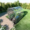 A greenhouse in a garden setting with trees and grass. Produktbild-Vorschau