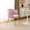 A pink velvet chair with gold legs is placed in a room with a white table and a cabinet in the background. Produktbild-Vorschau