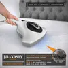 A hand holding a white and gray handheld vacuum cleaner over a white mattress, with a close-up of a dust mite in an inset. Produktbild-Vorschau