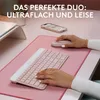 A person's hands are using a pink keyboard and mouse on a pink desk mat, with a phone and laptop stand in the background. Produktbild-Vorschau