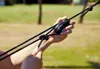 Hands adjusting a black rope with a black plastic adjuster, outdoors. Anteprima dell’immagine prodotto