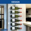 A modern kitchen with a stainless steel refrigerator and a black metal wine rack mounted on the wall, holding six green wine bottles. Produktbild-Vorschau