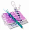 Two handmade craft items, possibly pens or charms, are placed on top of a spiral-bound notebook. One item is a blue and green twisted cord with a blue bead and some plastic strands. The other is a white and purple twisted cord with a small figure at the to Anteprima dell’immagine prodotto