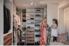 A woman and a child are in a walk-in closet, looking at clothes. Anteprima dell’immagine prodotto