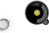 A black grain mill attachment with a yellow center is shown on a white background, next to a sieve filled with white powder. Anteprima dell’immagine prodotto