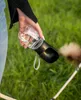 A person holding a dog water bottle outdoors on a grassy area. Produktbild-Vorschau