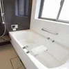 A clean, modern bathroom with a bathtub and a shower chair placed inside the tub. Voir les images du produit