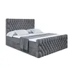A dark gray upholstered boxspring bed with a tufted headboard and footboard, made up with white bedding and a gray throw blanket, is shown against a white background. Produktbild-Vorschau