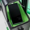 A smartphone is placed on a green charging tray, which is part of a black gaming locker. The phone screen displays the time and date. Podgląd zdjęcia produktu