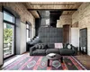A spacious living room with exposed brick walls, wooden ceiling, and a large dark gray sectional sofa. Anteprima dell’immagine prodotto