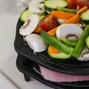 A close-up view of a multi-level cast iron rack filled with various chopped vegetables, including mushrooms, zucchini, carrots, tomatoes, and green peppers. Produktbild-Vorschau