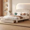 A bedroom scene featuring a bed with storage drawers, decorative shelves with lighting, and a tablet on the bed. Produktbild-Vorschau