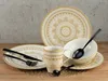 A set of dinnerware with a mandala pattern is arranged on a wooden surface against a textured gray background. Náhľad obrázku produktu
