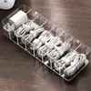 A clear organizer box filled with white charging cables and adapters, placed on a wooden desk. Produktbild-Vorschau